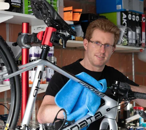 Niels aan het werk aan een fiets in zijn werkplaats, met een blauwe doek op het frame