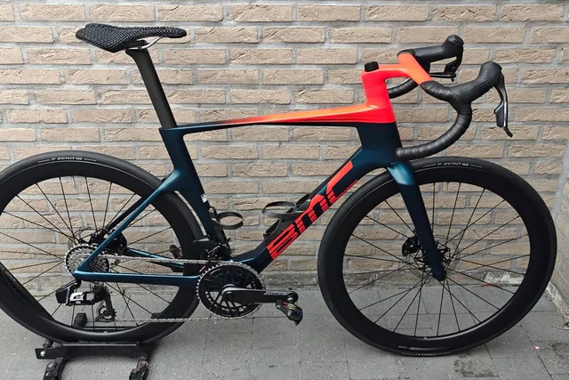 Blauw-oranje BMC aerofiets voor de bakstenen muur